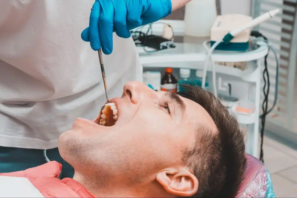 A dentist examining an adult male patient's teeth.