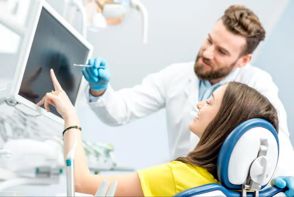 A dentist and female patient looking at a digital x-ray.