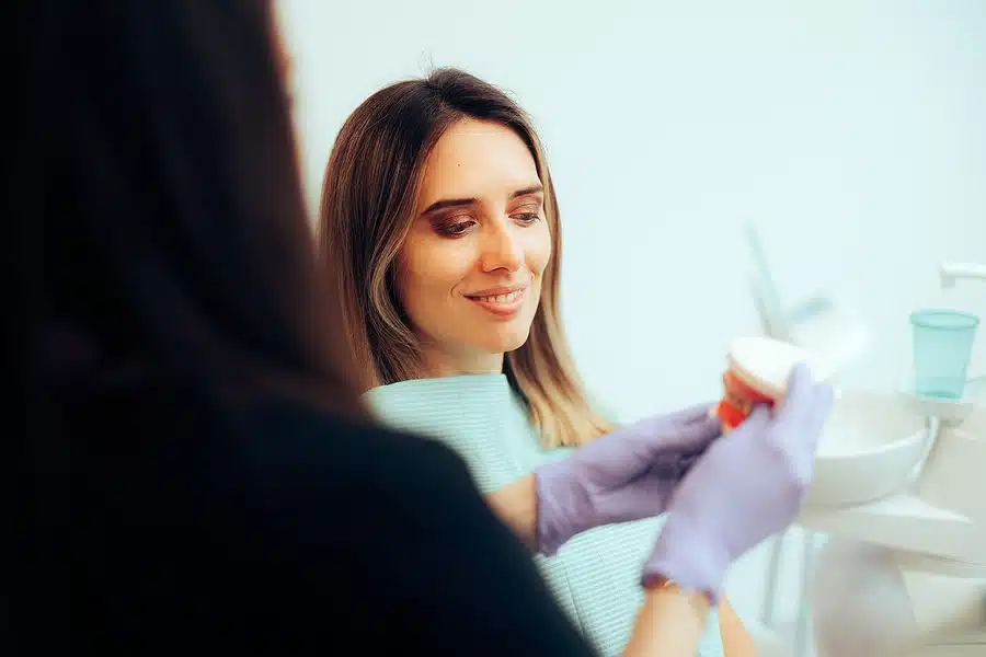 Dental professional explaining treatment with a tooth model